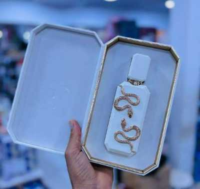 عطر بزجاجة بيضاء وأفعى ذهبية